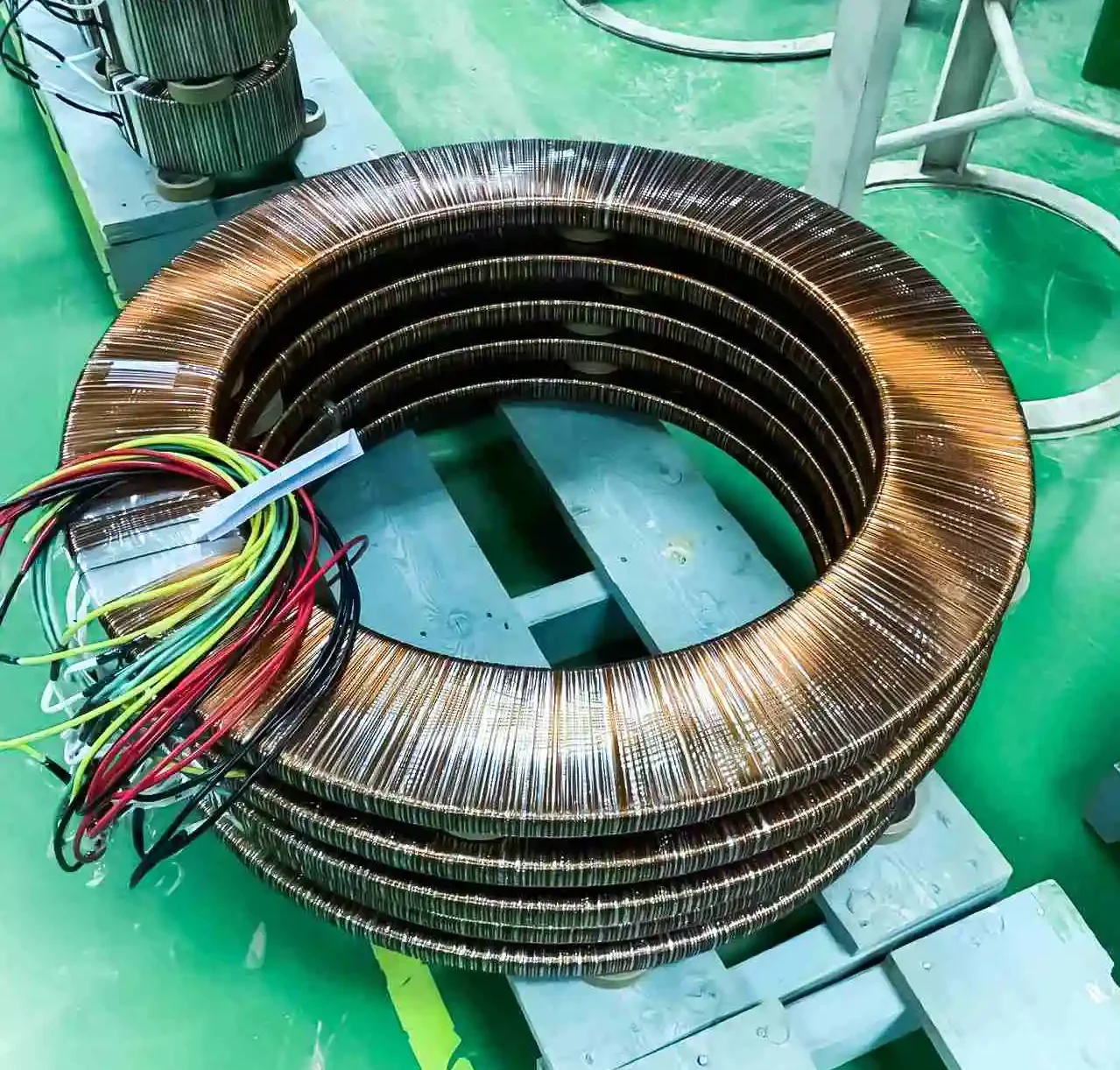 A coil of wire on a conveyor belt part of a Floor Type Toroidal Transformer Winding Machine coil