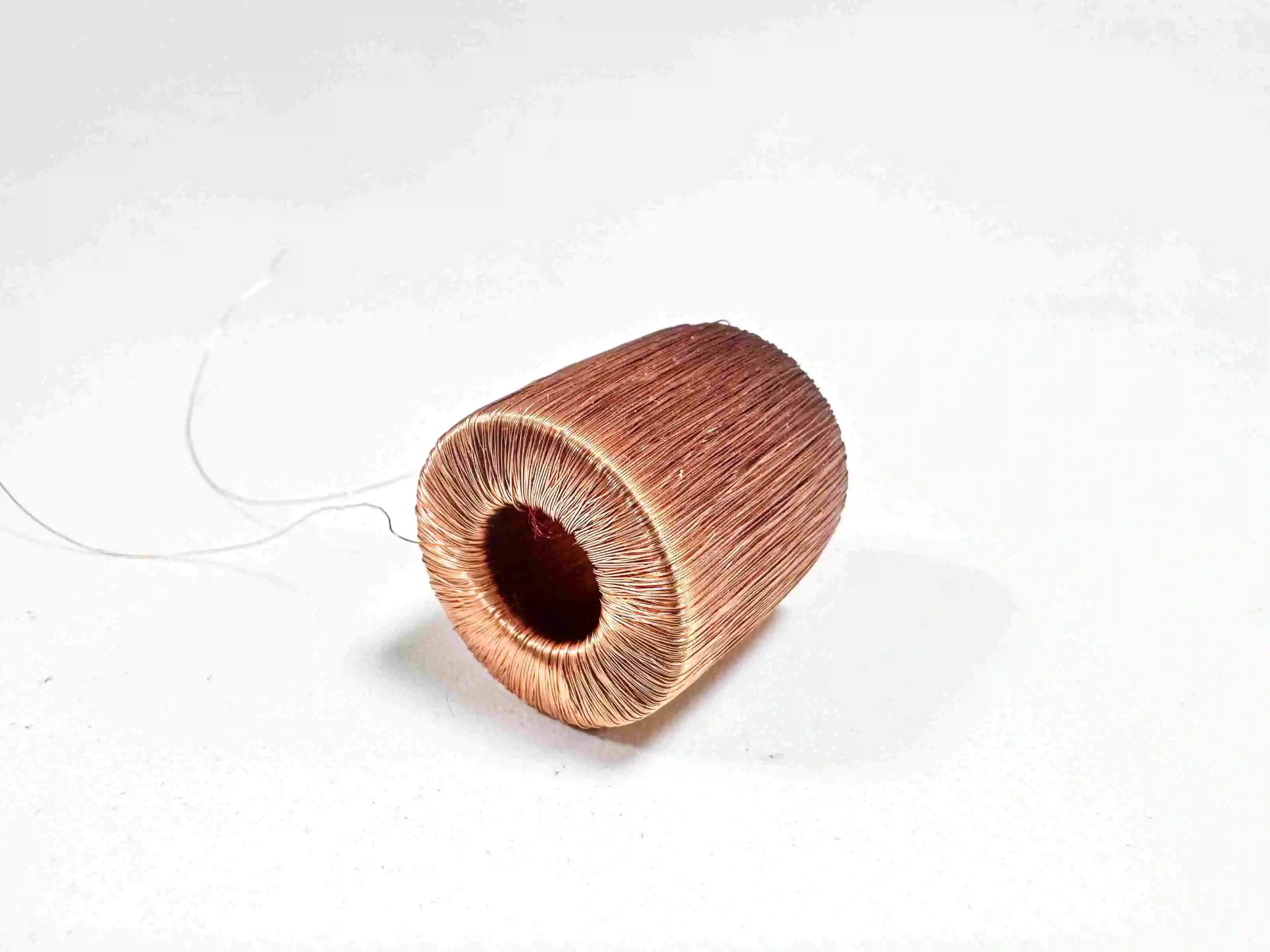 A small wooden object with a wire attached next to a high tube coil