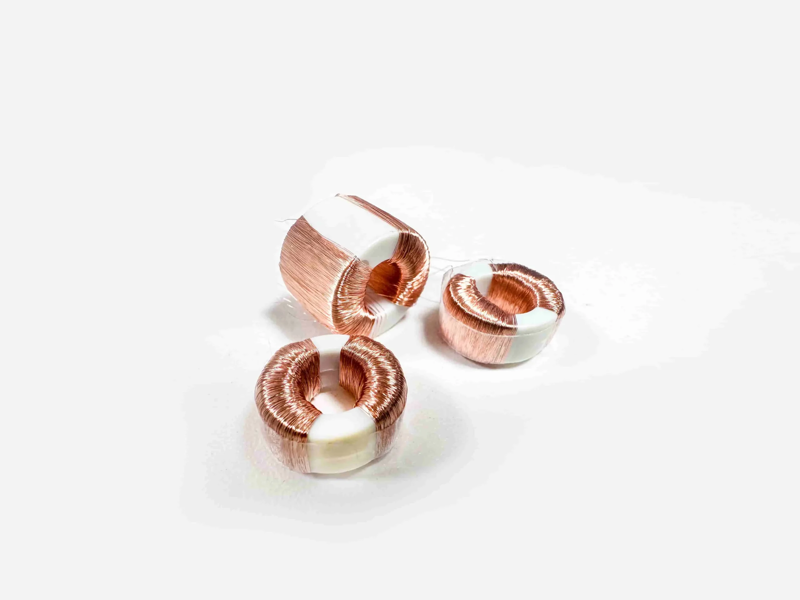 Three copper and white rings on a white surface representing a common mode coil