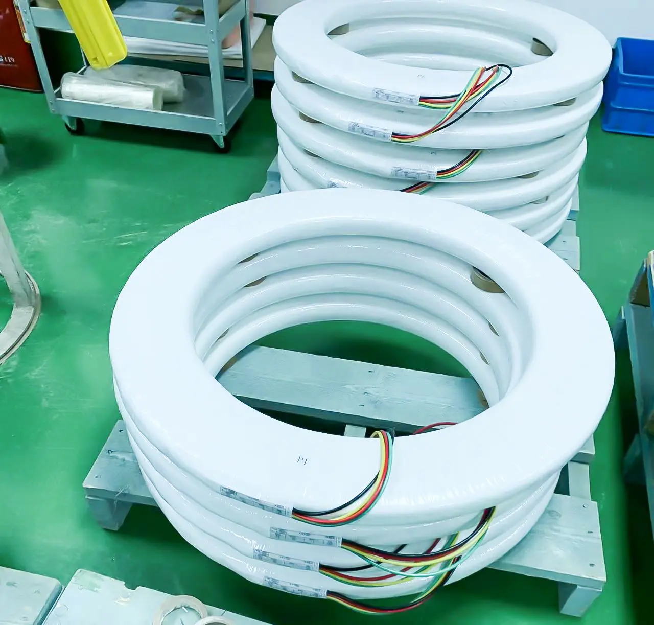 White circular tubes on pallet part of Floor Type Toroidal Transformer Winding Machine coil