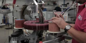 Un uomo che aziona una macchina che produce un filo rosso Questa immagine mostra la Transformer Winding Machine e la sua tecnologia