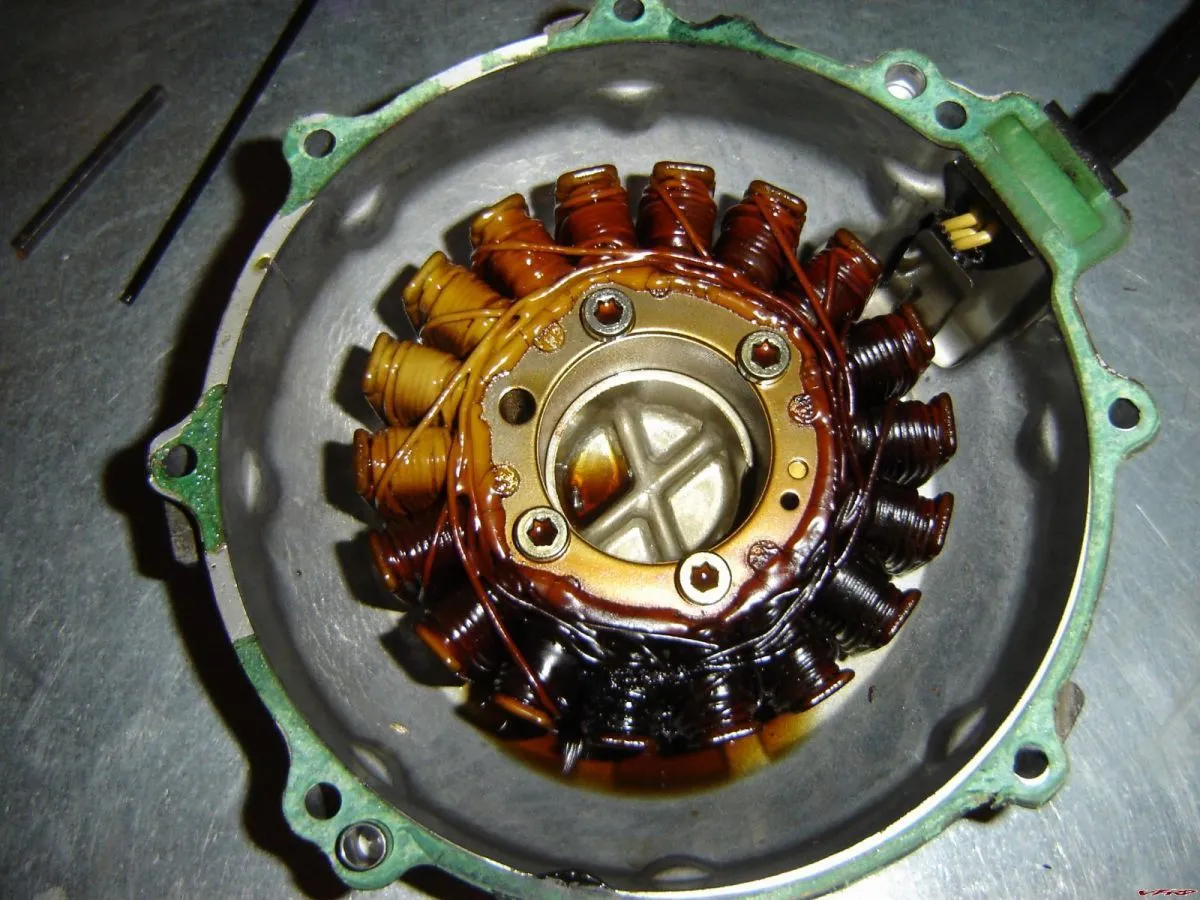 Damaged motorcycle stator with discolored windings indicating potential overheating and electrical malfunctioning highlighting bad stator symptoms Damaged motorcycle stator with discolored windings indicating potential overheating and electrical malfunctioning highlighting bad stator symptoms