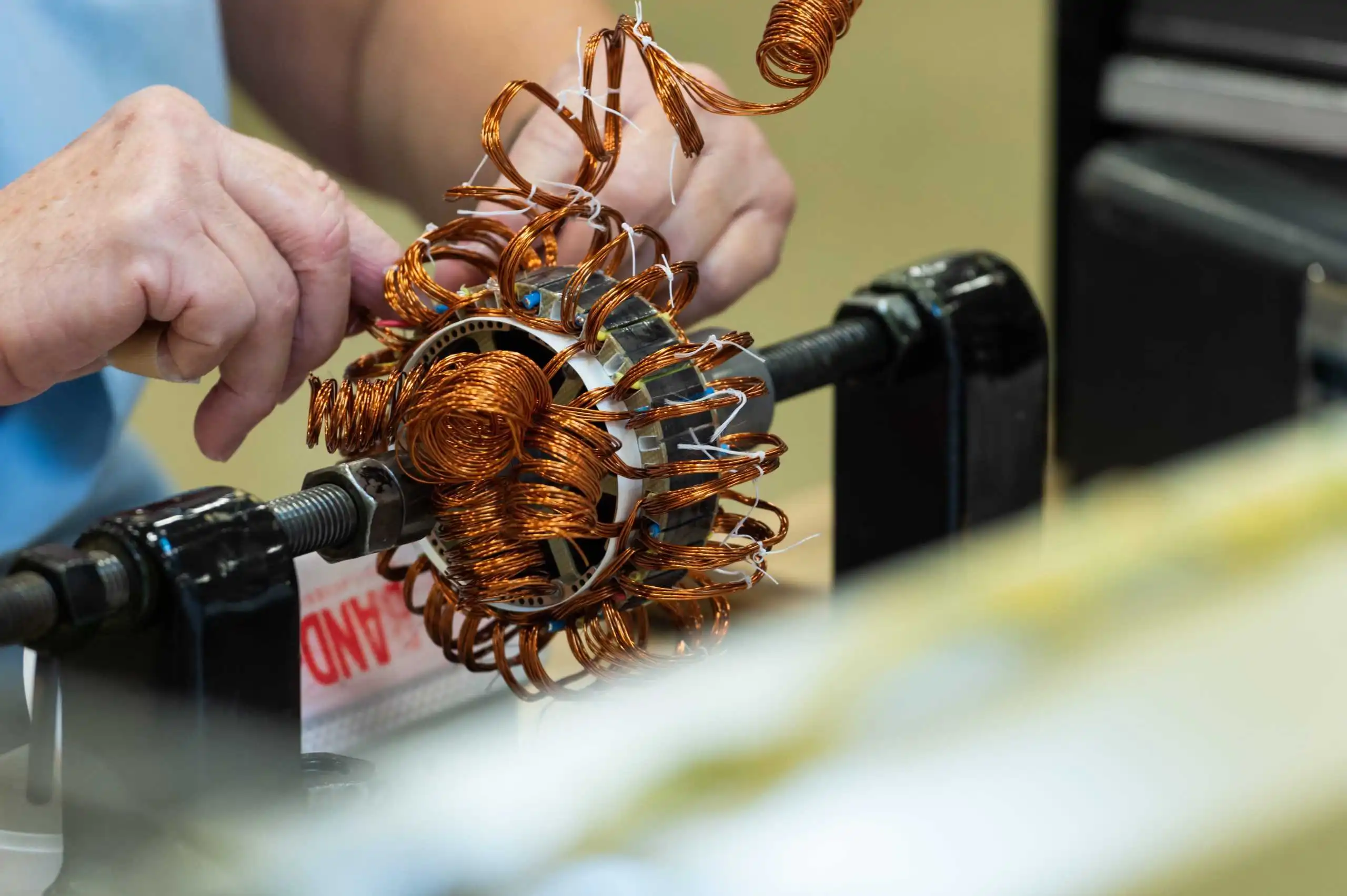 Ein Techniker führt sorgfältig das Wickeln von Spulen für elektronische Systeme in Militärqualität durch