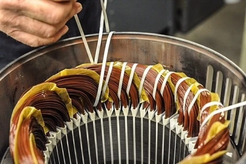 Operaio che fissa gli avvolgimenti della bobina all'interno di uno statore del motore